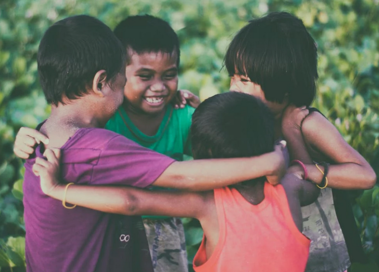 Four children laughing with their arms around each other