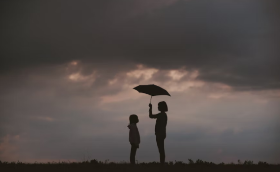 Two children standing under an umbrella as dark clouds gather