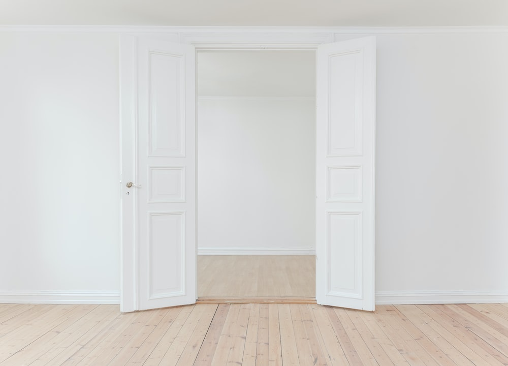 A white wall with a white door in the middle of it.
