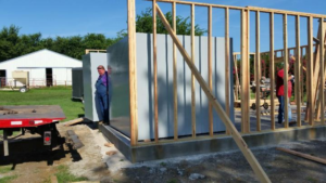 Several people are carrying out a steel tornado shelter installation.