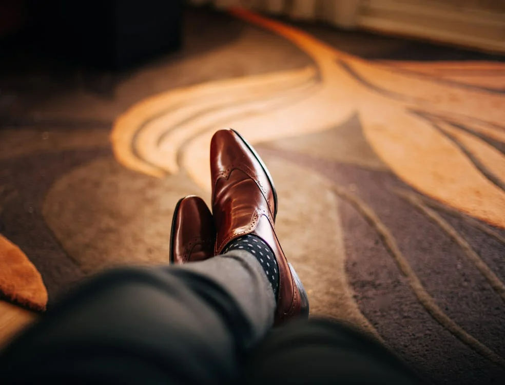 Legs with luxury shoes on the feet on a warm-toned carpet