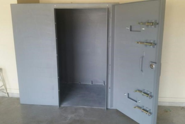 A large, heavy-duty gray metal safe with its reinforced door open, revealing an empty interior.