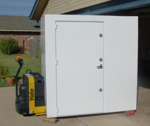 A large white steel security door or safe room door being moved with a Yale electric pallet jack.