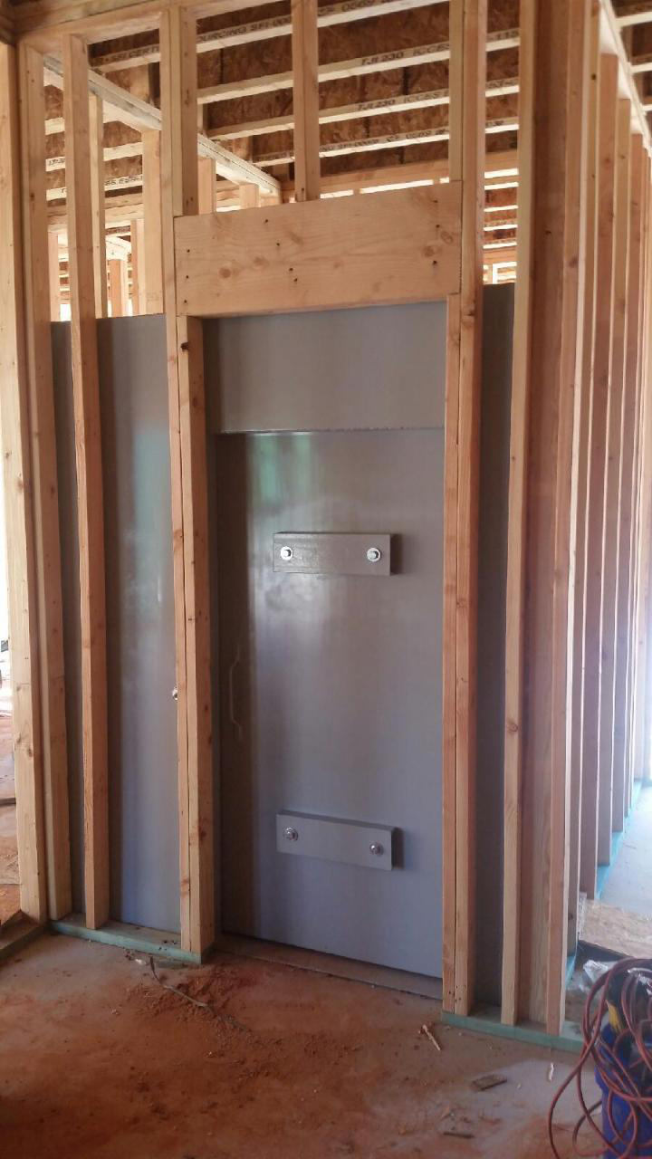 A steel safe room door framed by wooden beams