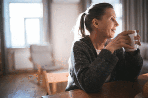 Senior woman holding a cup and sitting comfortably in a furnished room