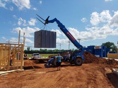 Steel storm shelter being lifted into place.