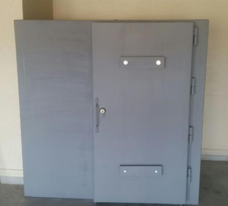Gray steel tornado safe room with reinforced door.