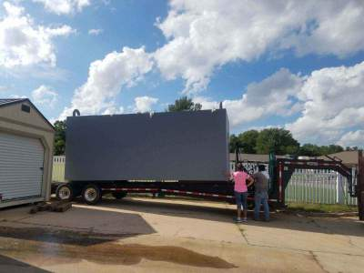 Large residential safe room delivered on a trailer at a suburban home for installation