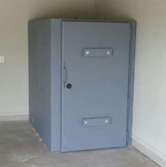 Reinforced steel safe room installed inside a residential garage with a heavy-duty secure door.